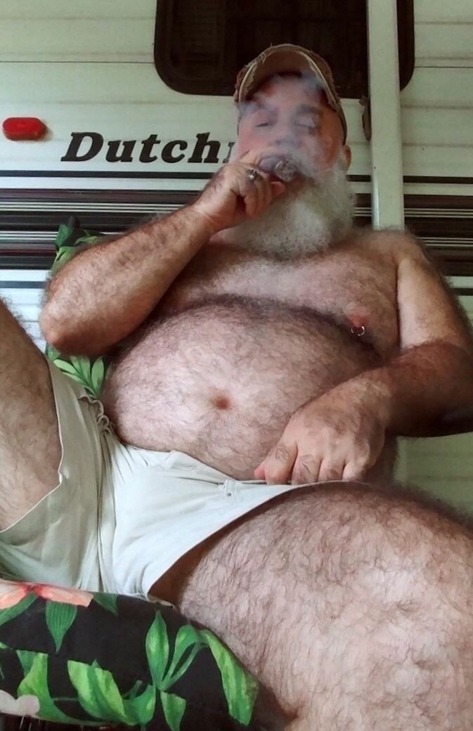 sexy guy with white hair smoking a cigar wearing thin shorts with the tip of that cock showing picture
