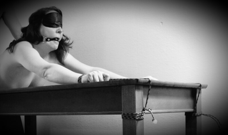 Brunette sex slave blindfolded & tied to table picture