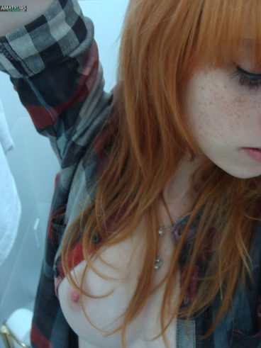 Nude redhead takes a selfie of her tiny tits. picture