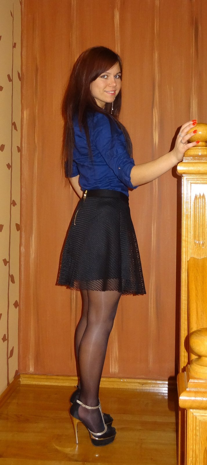 Very pretty young girl in shiny nylon stockings, black mini skirt, silk blue blouse and black'n golden high heeled sandals picture
